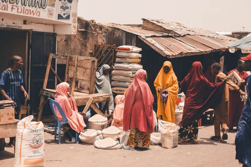 Free Colorful street market in West Africa with people and vibrant textiles. Captures daily life and commerce. Stock Photo