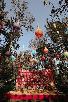 Vibrant outdoor setup with colorful paper lanterns and decorated table under trees.