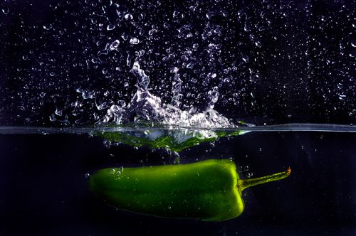 Free Dynamic shot of a green bell pepper splashing into water, creating bubbles and reflections. Stock Photo