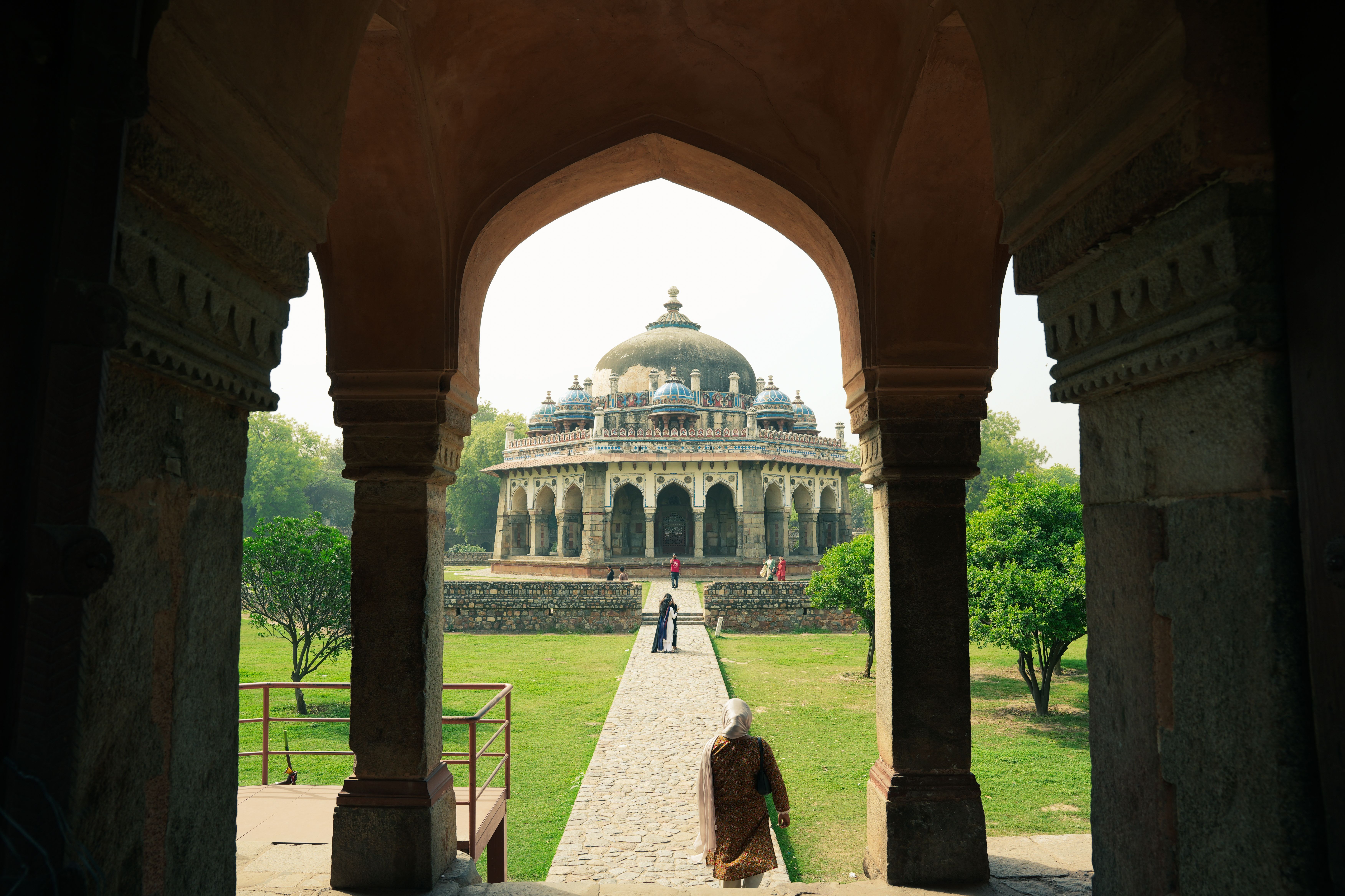 A wide paved ramp leading into a Delhi monument garden with visitors walking