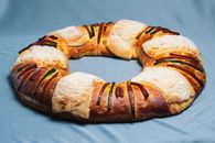 Colorful Rosca de Reyes bread on a blue cloth, showcasing festive Mexican pastry traditions.
