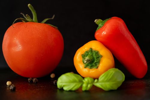 Free Vibrant still life of fresh tomatoes, peppers, and basil on a dark backdrop, showcasing natural textures and colors. Stock Photo