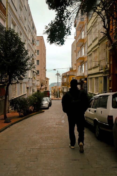 Free Man walking on a cobblestone street between apartment buildings. Stock Photo