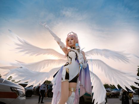 An outdoor cosplay photoshoot featuring a person with angelic wings at sunset.