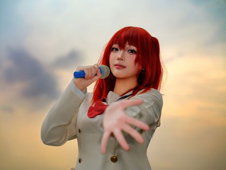 A captivating cosplay performer holding a microphone in an outdoor sunset setting.