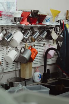 A neatly arranged kitchen pegboard with coffee mugs, kitchen items, and shelves for organization.