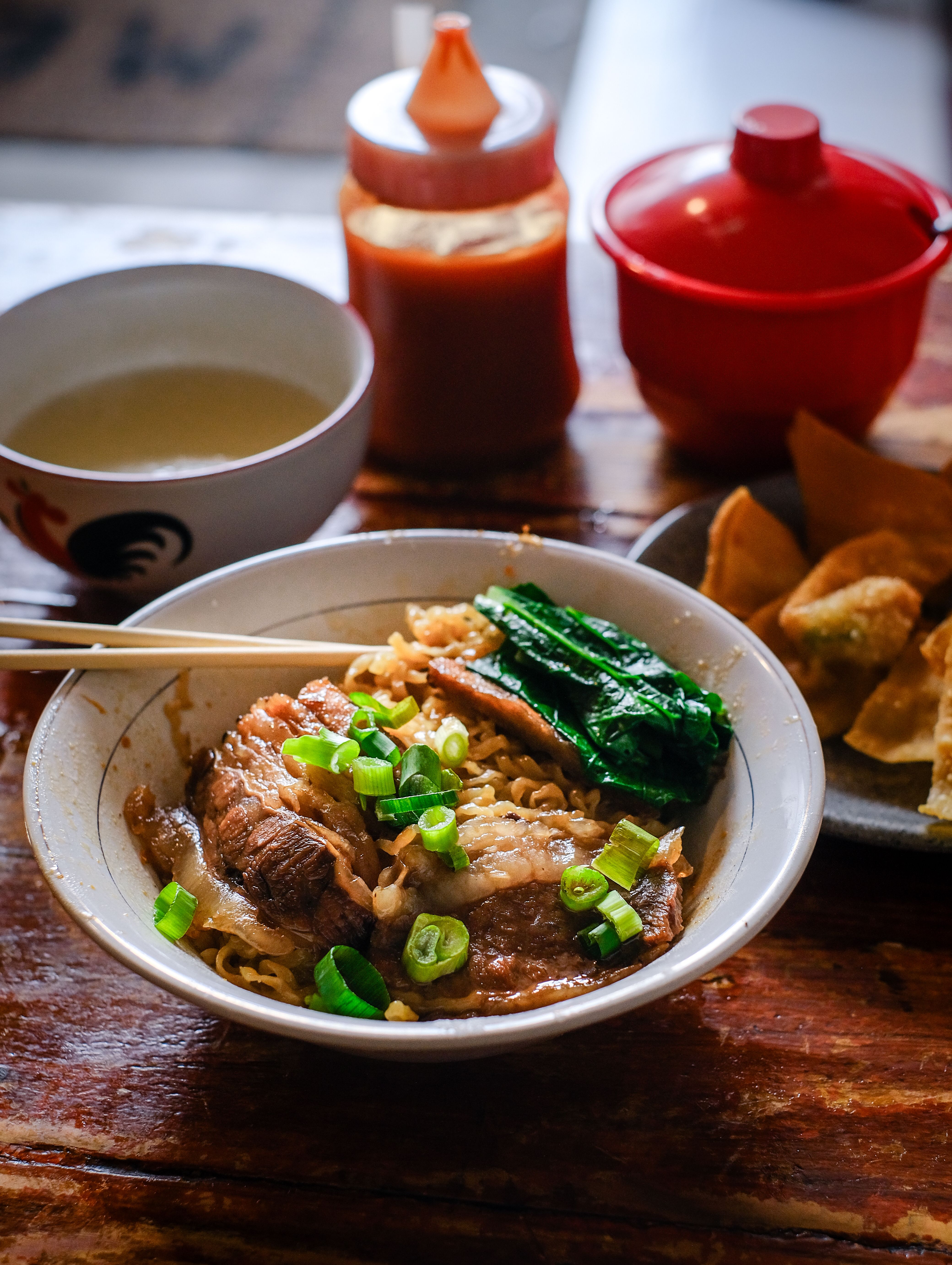 A savory bowl of Indonesian beef noodle soup with green onions and bok choy.