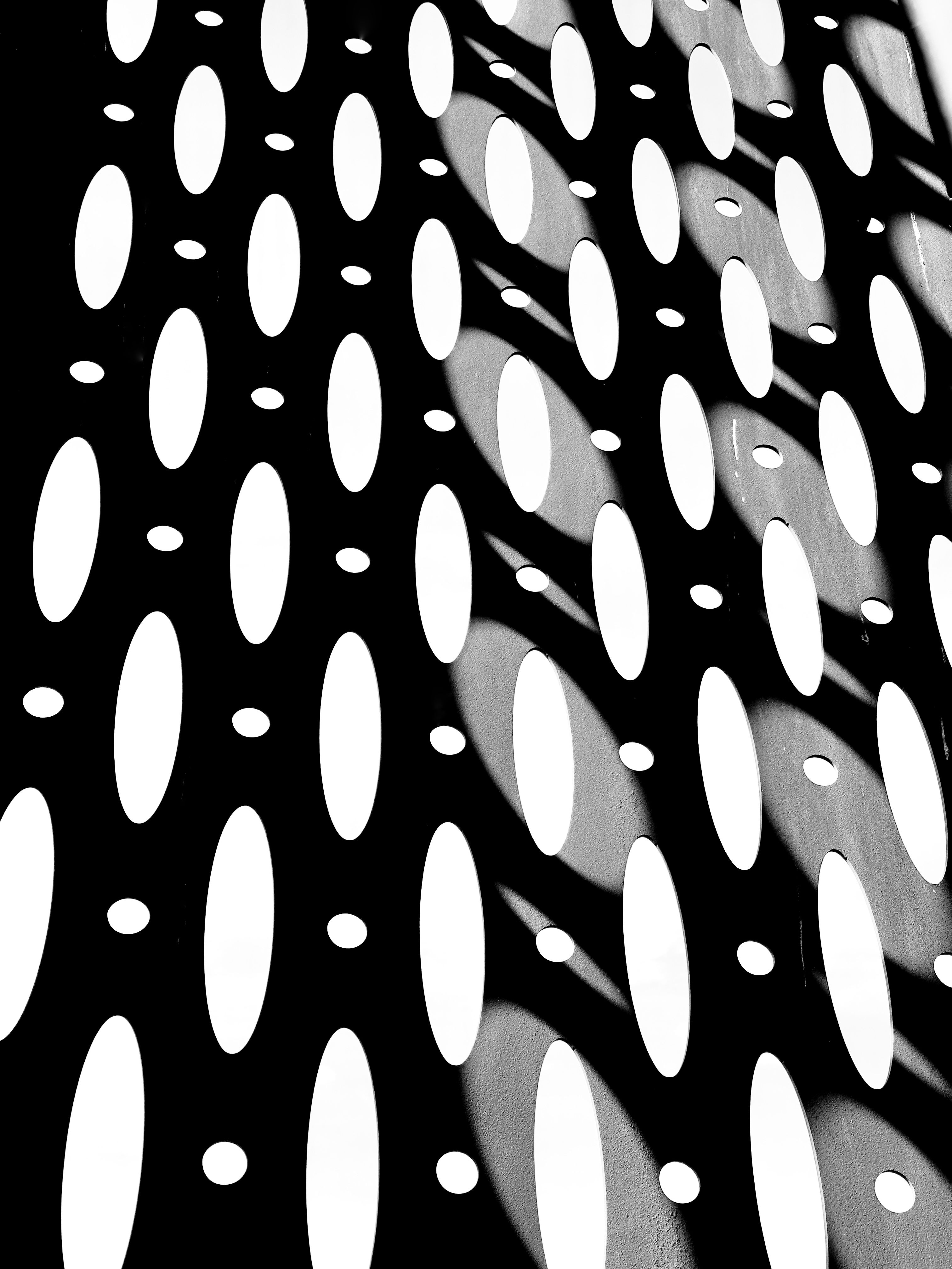 Dynamic geometric pattern with oval shapes and dramatic shadows in black and white.
