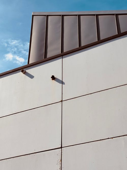 Free Minimalist modern architecture featuring sharp geometric lines and clear blue sky. Stock Photo