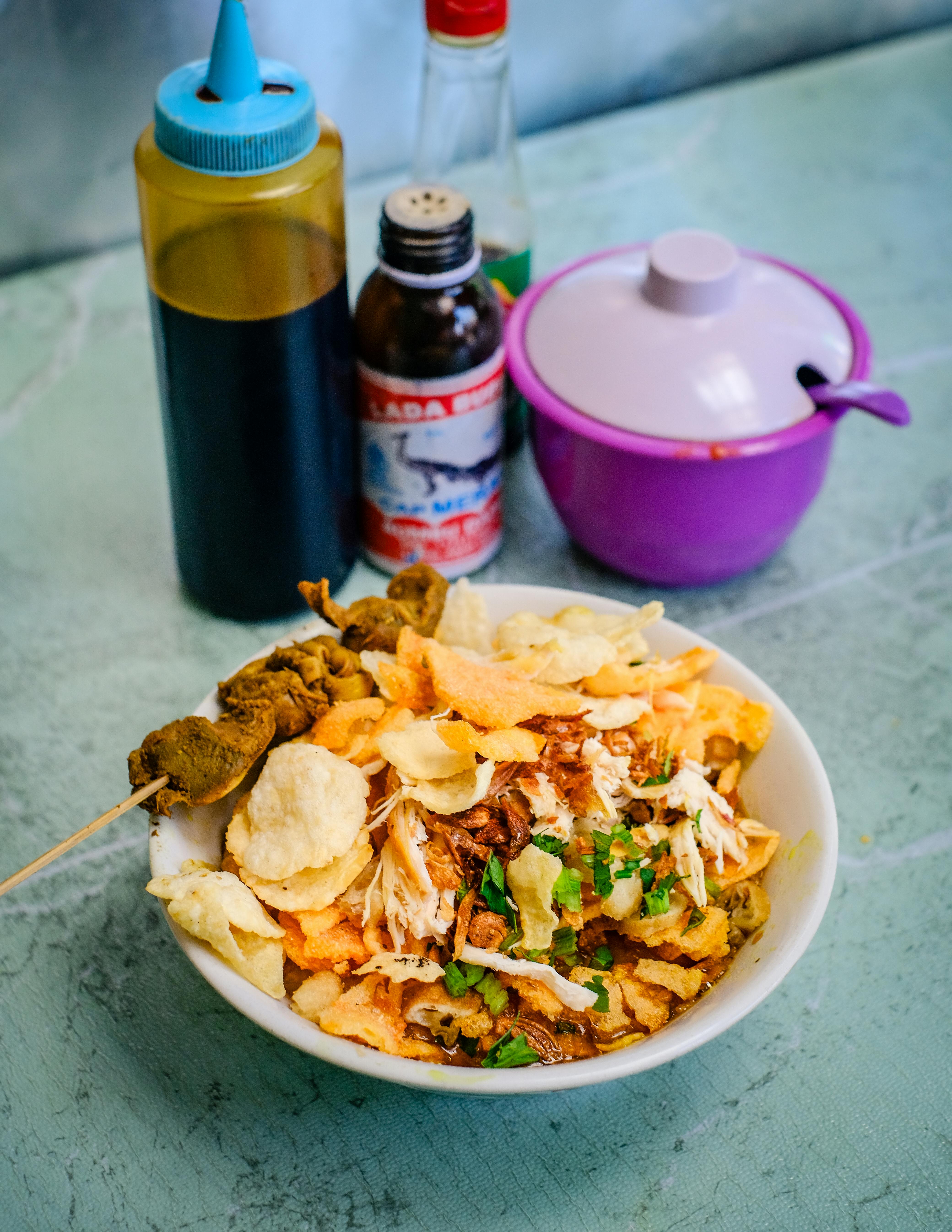 Bubur ayam Indonesia dengan kondimen dan kerupuk