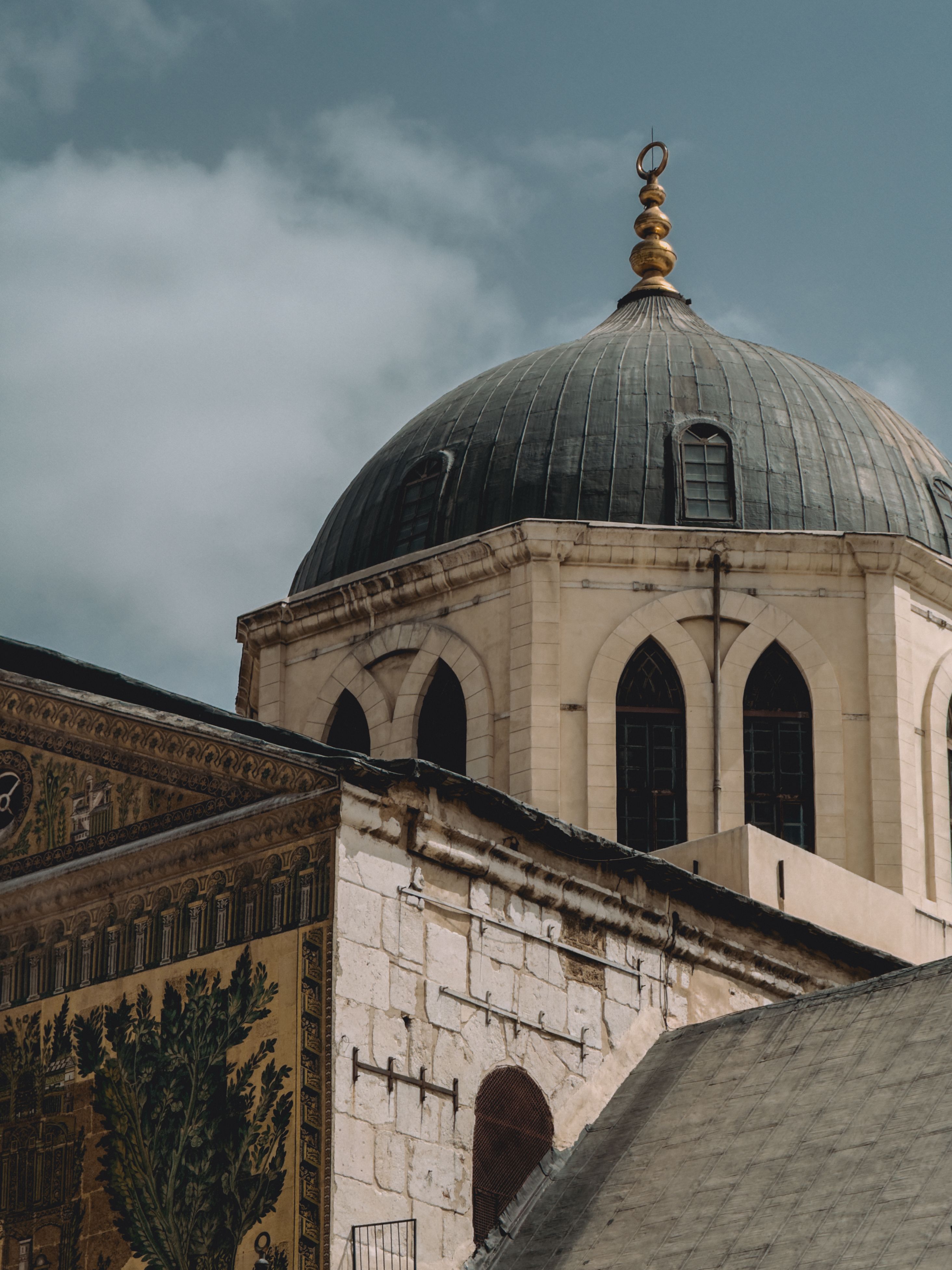 Gratis Fængslende udsigt over Umayyad-moskeens kuppel i Damaskus, der fremviser islamisk arkitektur mod en overskyet himmel. Lagerfoto