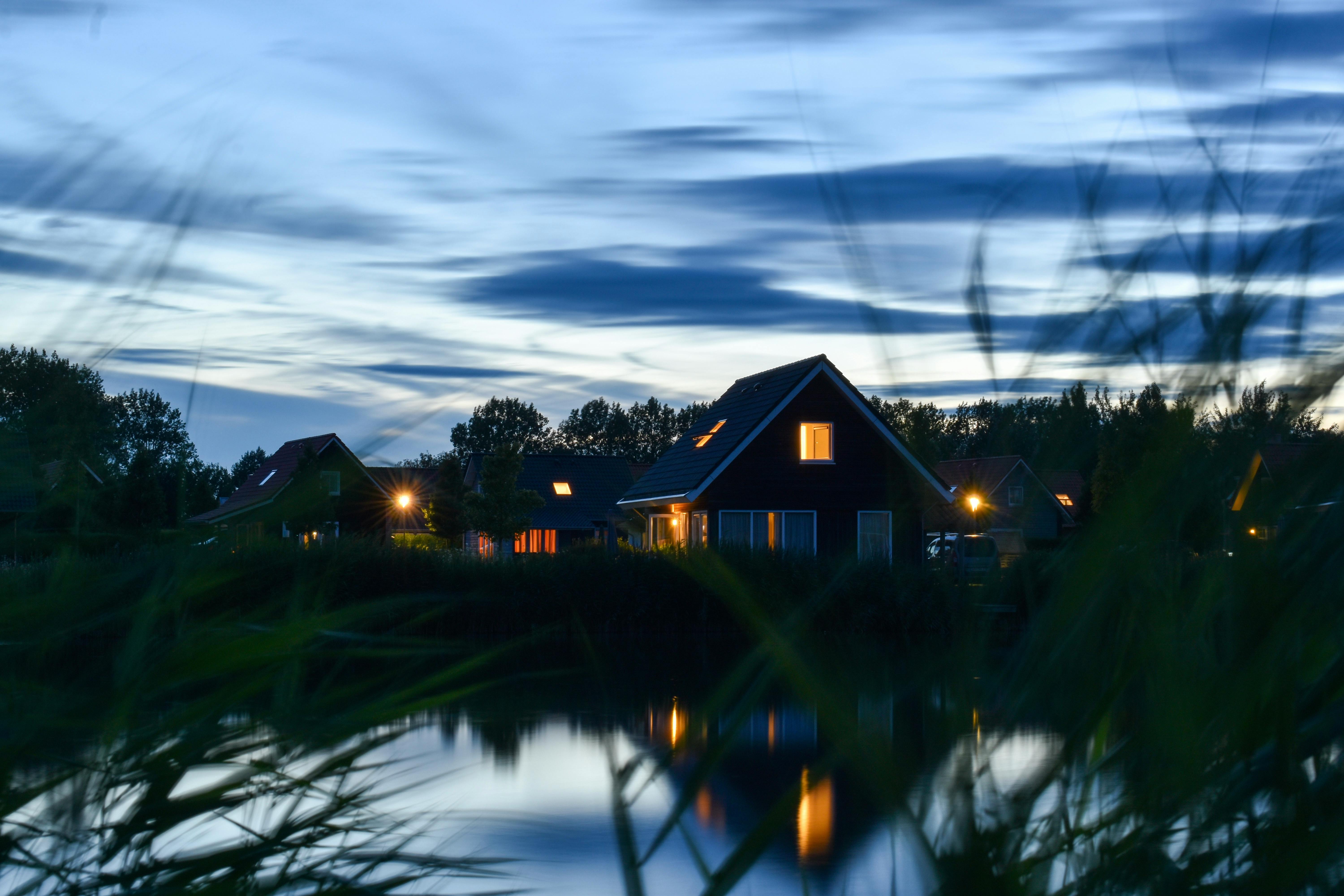 Charmant chalet au bord du lac, illuminé, reflétant la tranquillité du crépuscule.