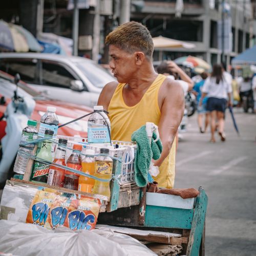 Free A street vendor in Manila sells drinks from a cart in a busy urban setting. Stock Photo