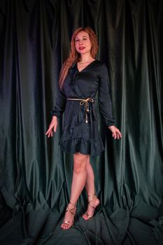 Stylish portrait of an elegant woman in a little black dress, showcasing modern fashion against a dark backdrop.
