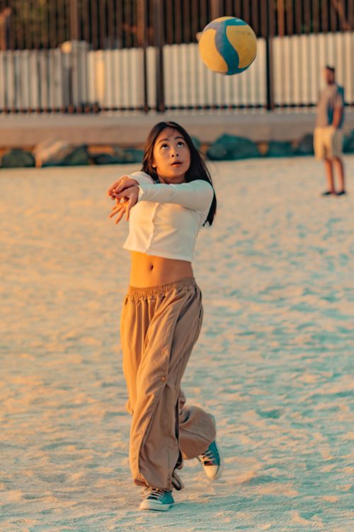 Free Young woman enjoying a volleyball game on the sandy beach in Manila at sunset. Stock Photo