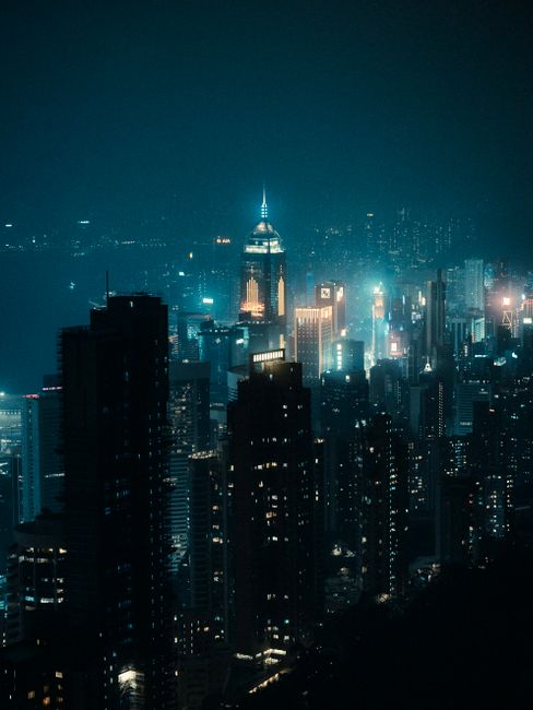 Stunning night view of Hong Kong skyline with illuminated skyscrapers reflecting on water.