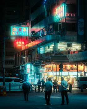 Neon-lit street with people and shops, capturing the essence of vibrant nightlife in an urban setting.