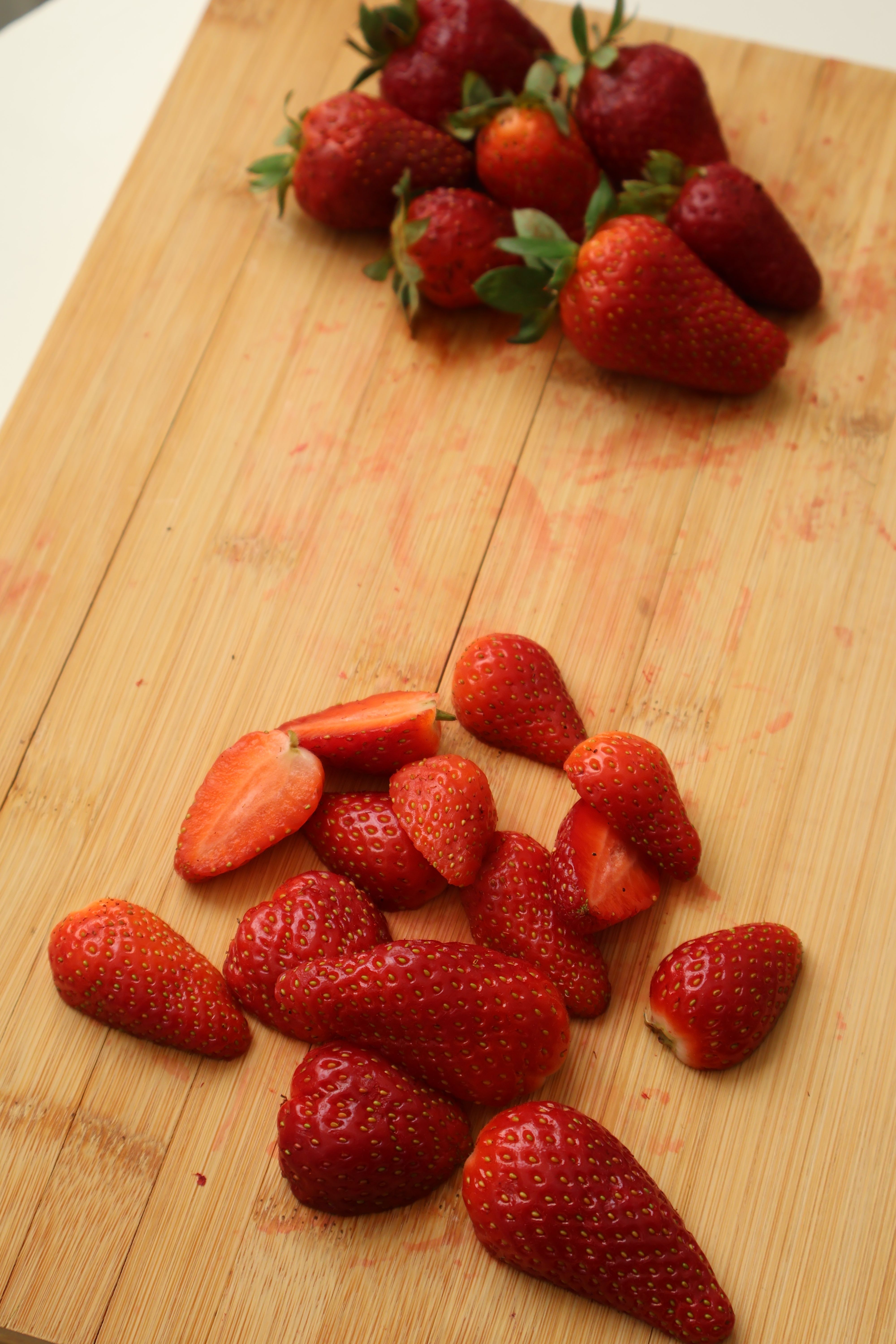 Strawberries with green tops removed on a cutting board