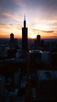 Dramatic aerial view of Chicago city skyline against a vibrant sunset backdrop.