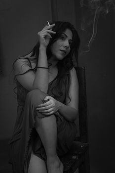 A dramatic black and white portrait of a woman smoking, conveying a moody and artistic vibe.