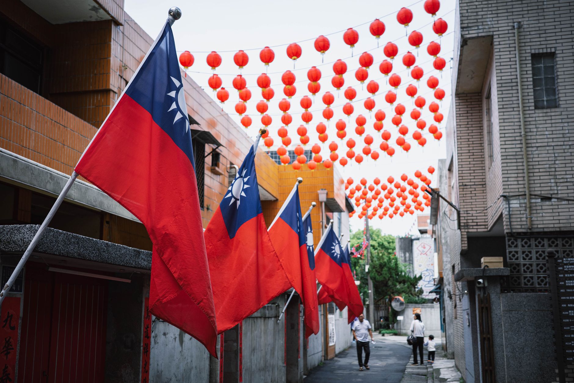 Colorful Taiwanese flags and red lanterns adorn an alley in New Taipei City, Taiwan, creating a festive atmosphere.