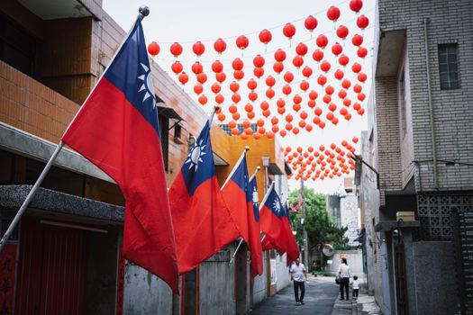 Colorful Taiwanese flags and red lanterns adorn an alley in New Taipei City, Taiwan, creating a festive atmosphere.