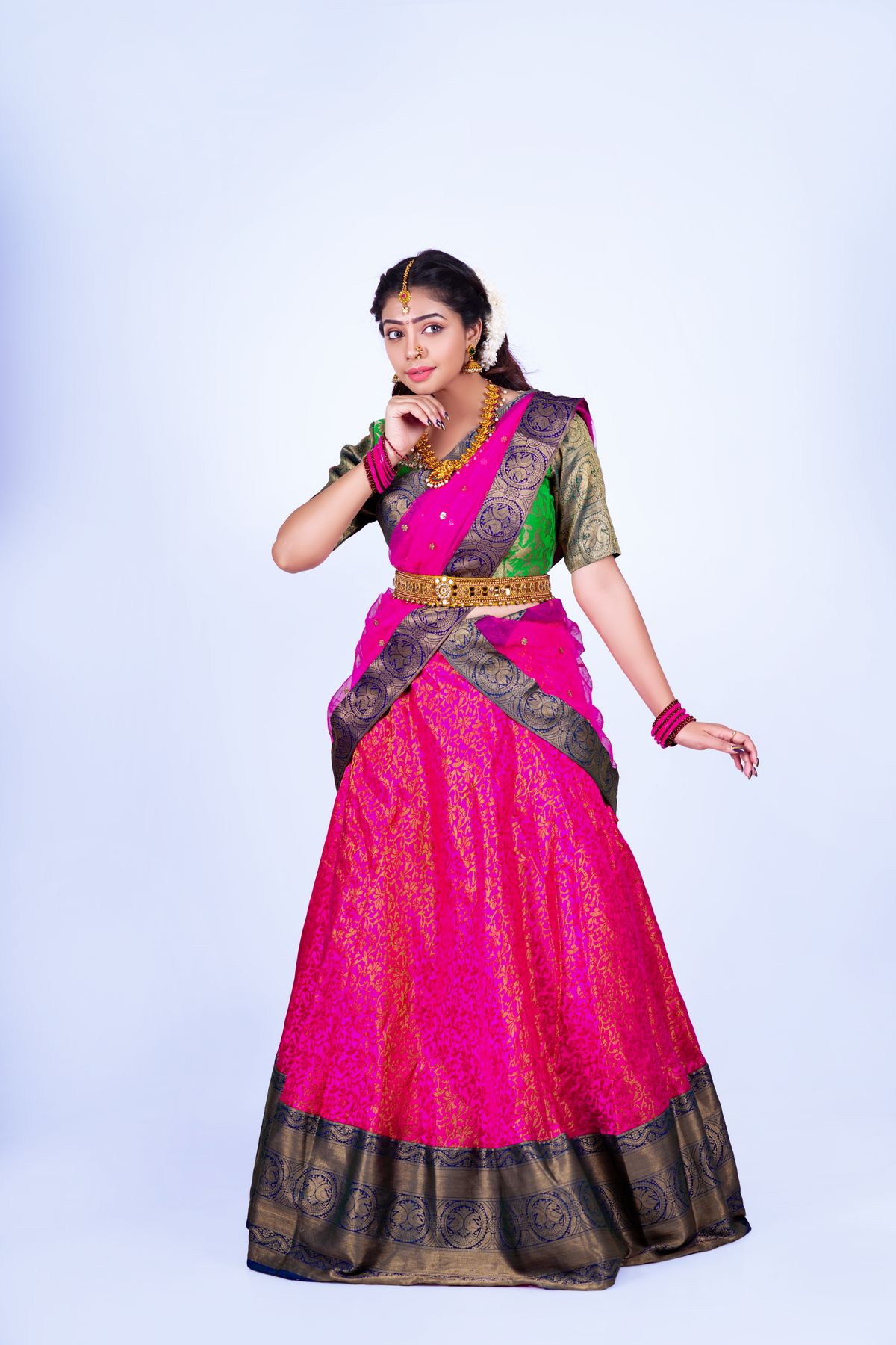Model wearing an elegant pink and green Indian saree with a gold border