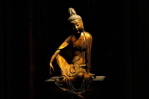 Free Bronze Buddha statue captured in low light, showcasing serene posture. Stock Photo