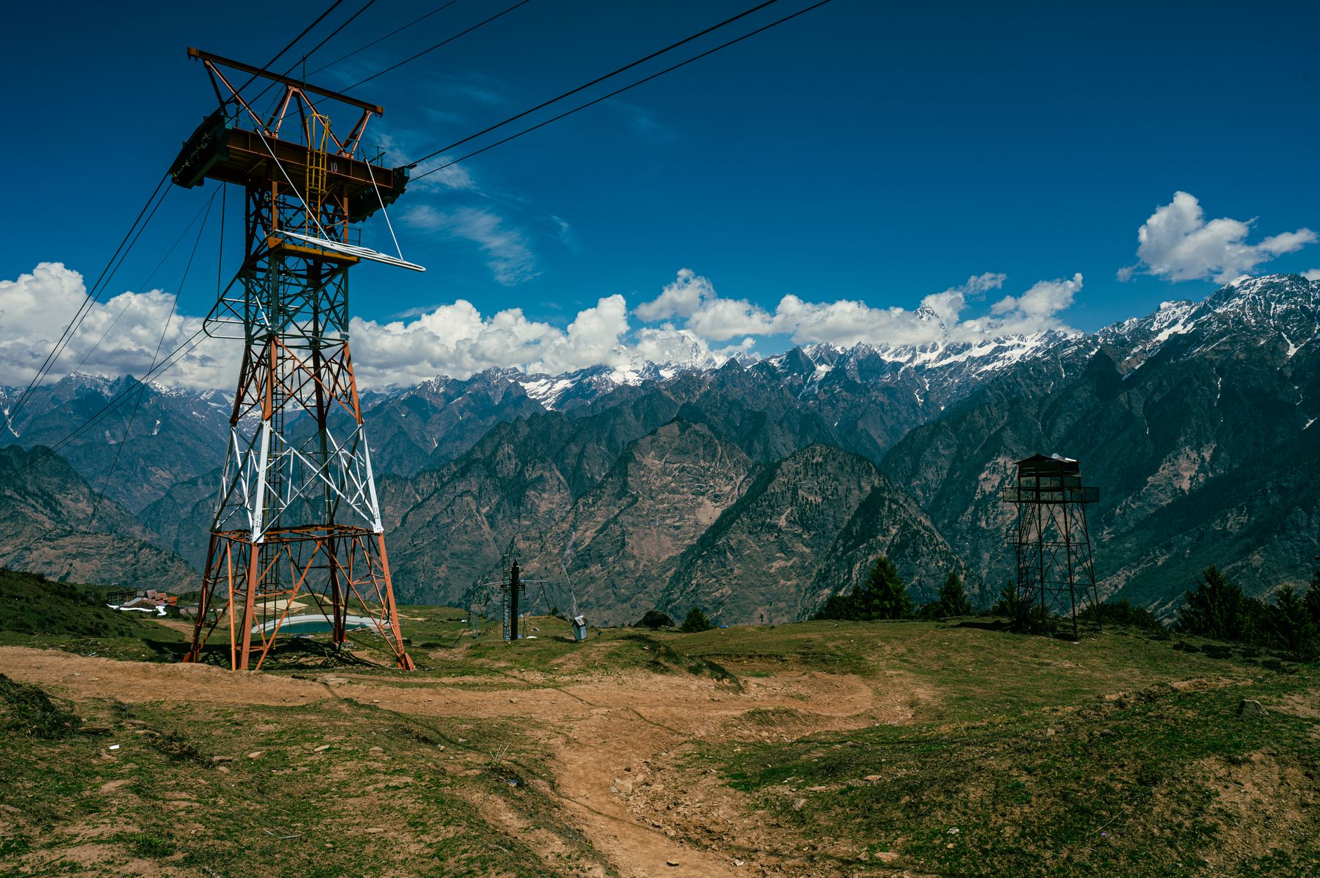 Experience the breathtaking snow-capped peaks of Auli, Uttarakhand, India, with a prominent cable tower in the foreground.