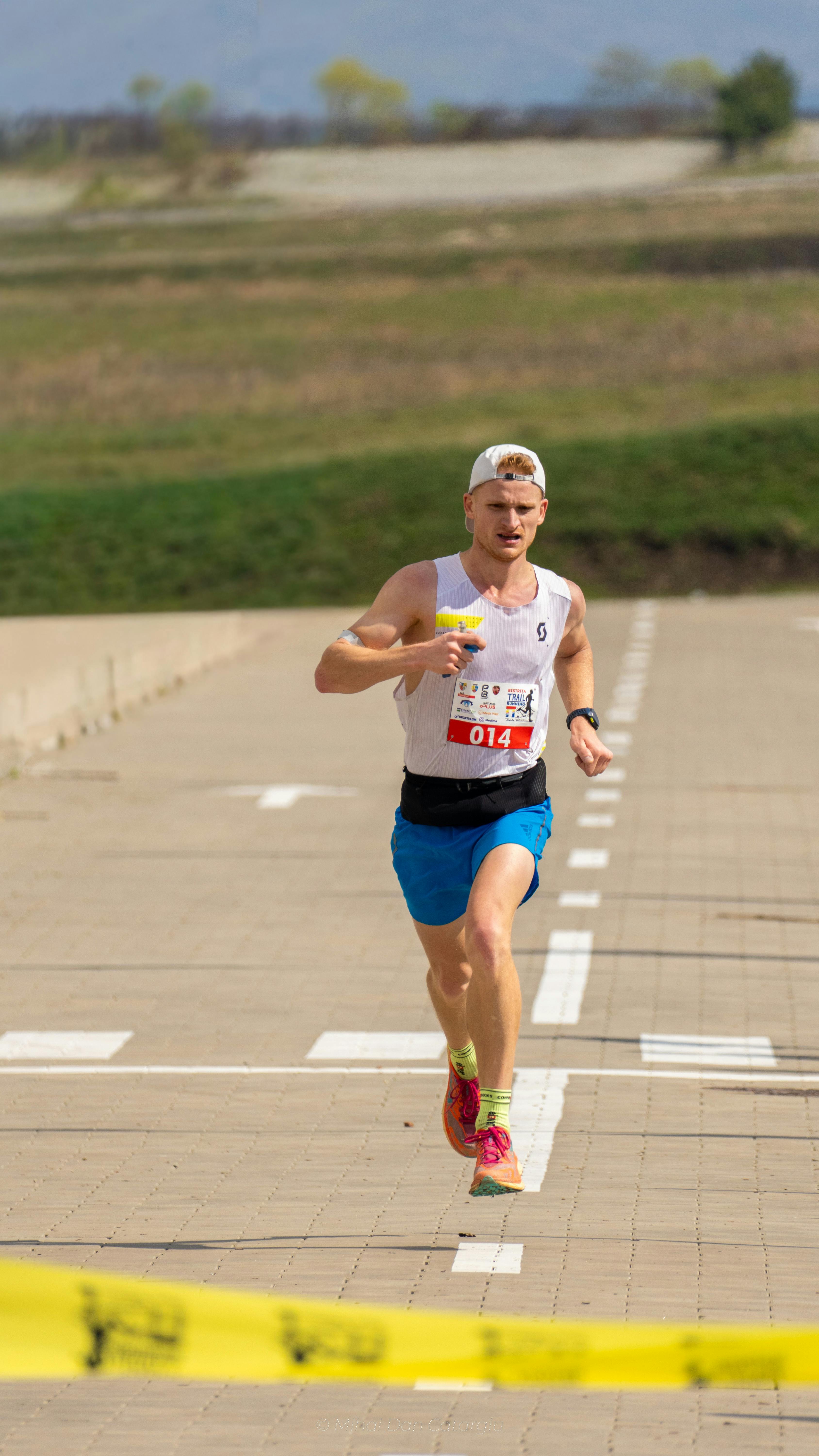 Athlete running a marathon outdoors on a sunny day, wearing race bib 014.