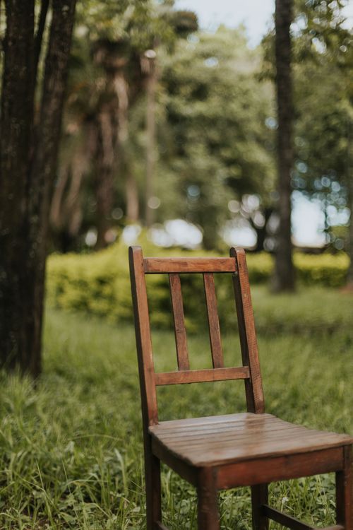 Free A rustic wooden chair placed in a lush green forest, creating a peaceful outdoor ambiance. Stock Photo
