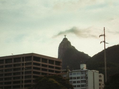 Free Christ the Redeemer statue on Corcovado Mountain with Rio de Janeiro cityscape under a cloudy sky. Stock Photo