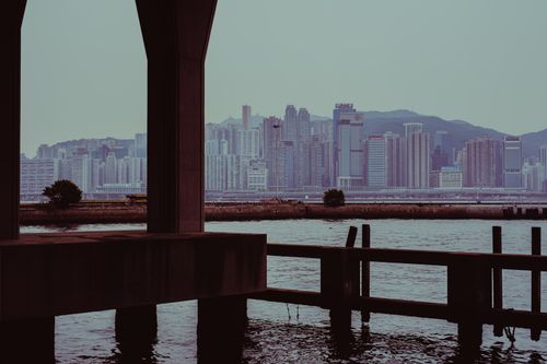 Free View of Kowloon skyline captured from a pier with a dramatic, moody atmosphere. Stock Photo