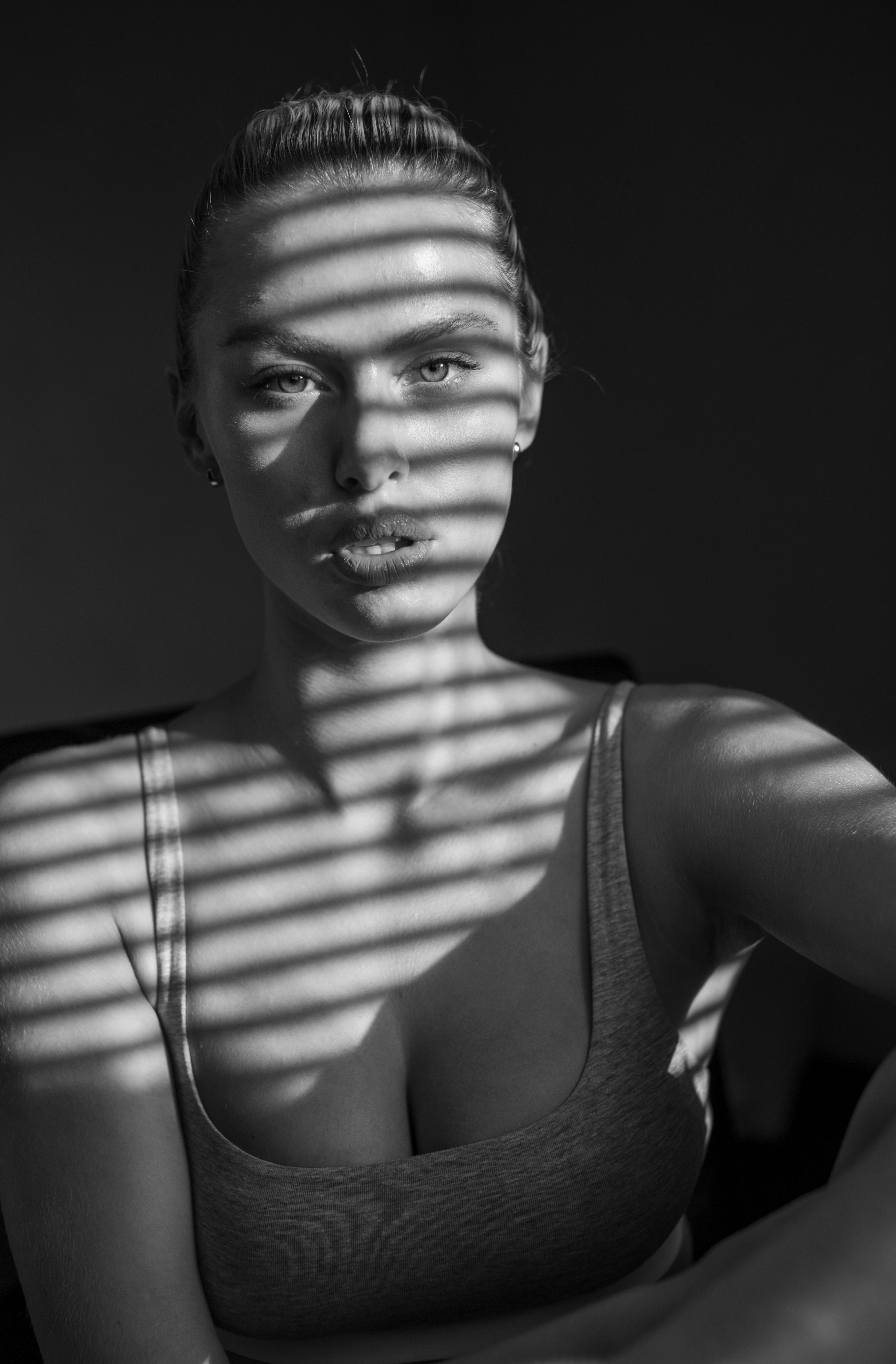 Elegant and dramatic black and white portrait featuring shadow play through window blinds.