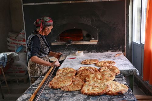 Free A woman baking traditional round bread in an indoor bakery setting. Stock Photo