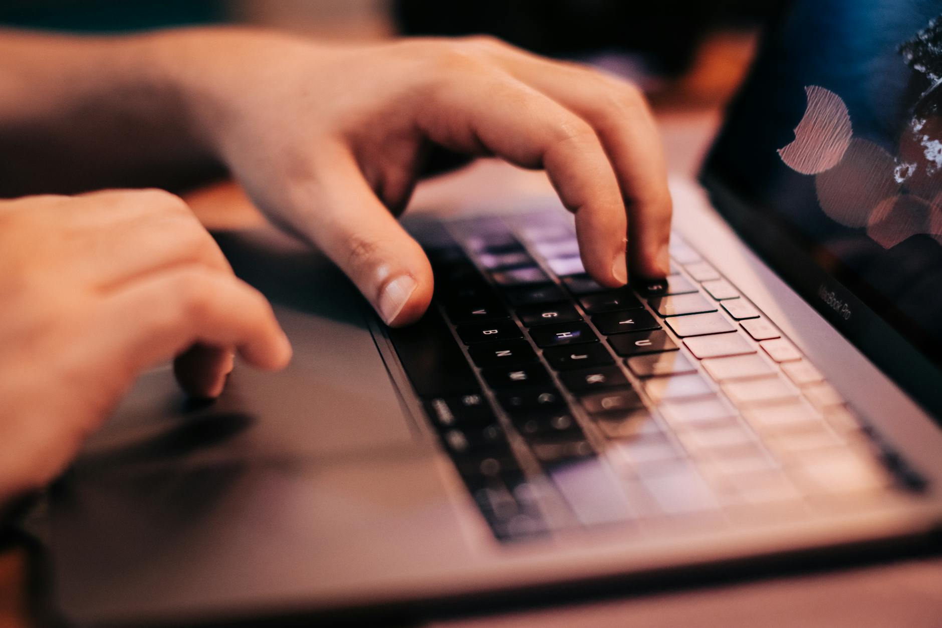 A person typing on a laptop with a fantasy world in the background