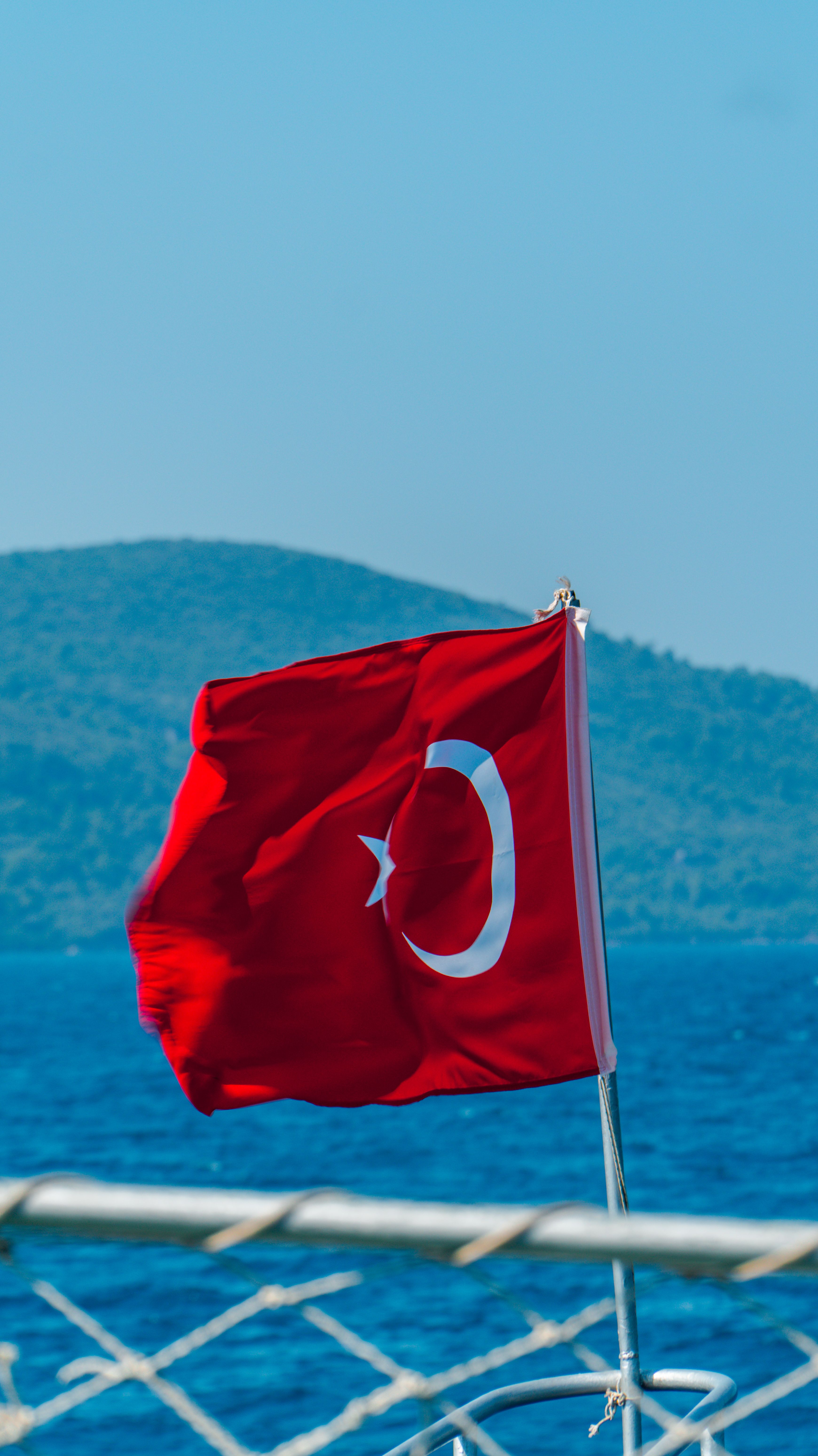 Turkish flag on a boat, captured against a stunning blue sea and mountain backdrop.