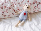 一只可爱的泰迪熊，心形图案，正躺在卧室里舒适的花卉枕头上