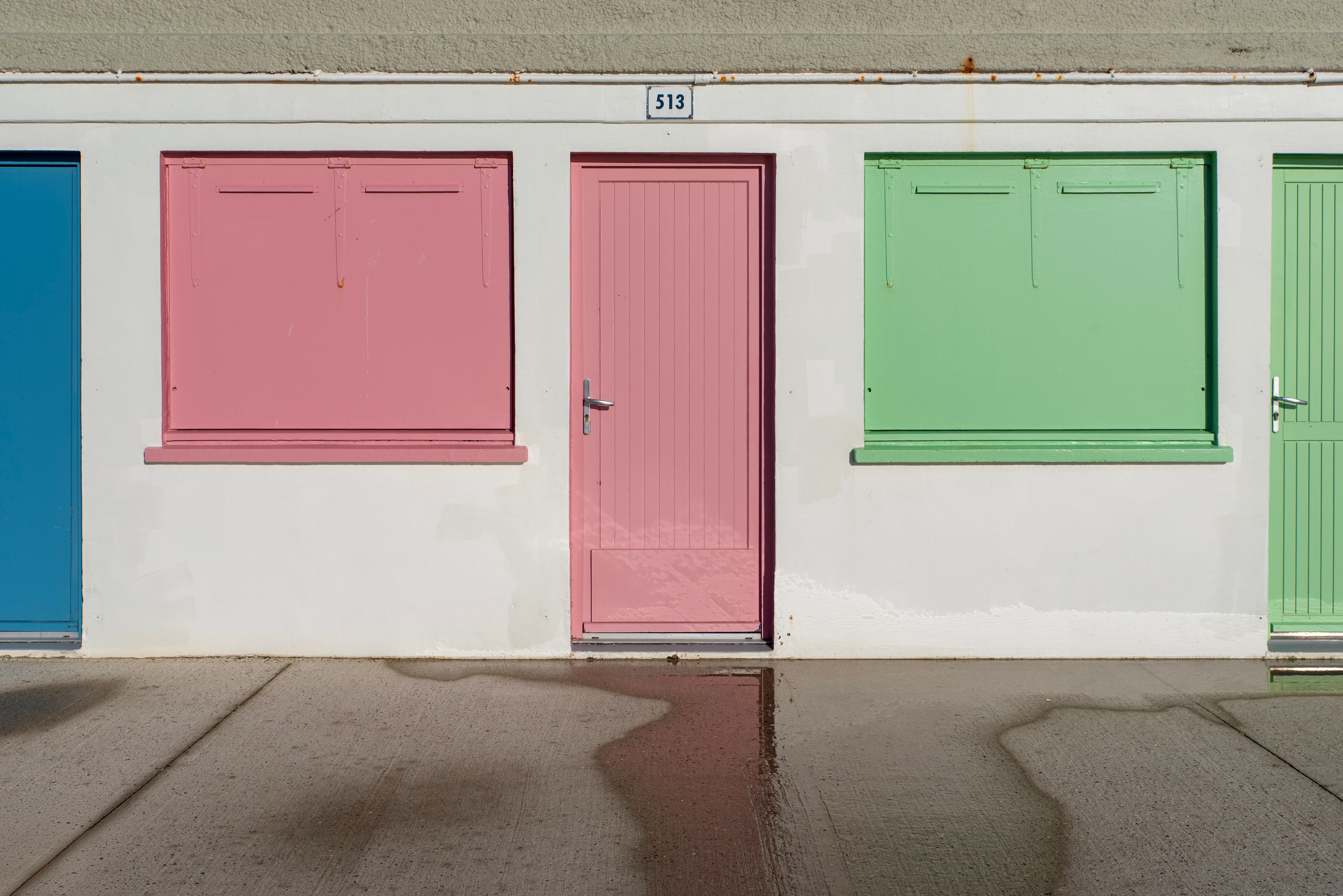 Vibrant blue, pink, and green garage doors on a city street wall, offering artistic contrast.