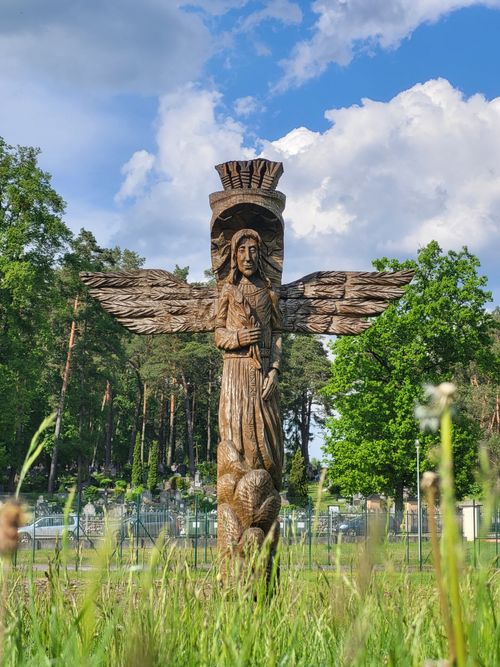 Free Detailed wooden sculpture with wings in a lush Lithuanian park setting. Stock Photo