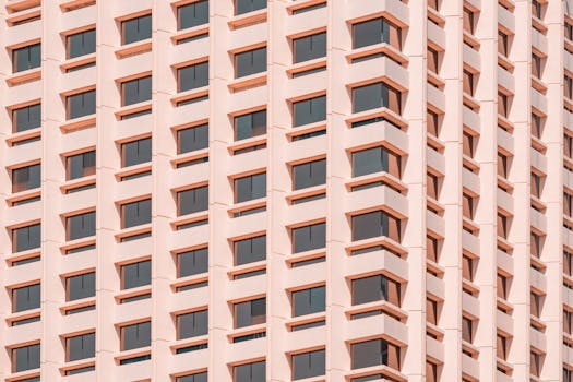 Low angle view of a modern pink building facade in Sydney with repetitive window patterns.