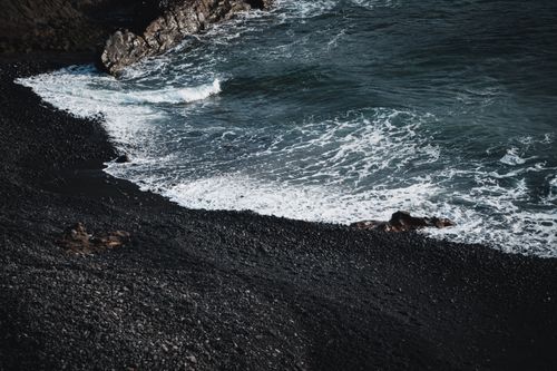 Free A mesmerizing view of Lanzarote's distinctive black sand beach meeting the Atlantic waves. Stock Photo