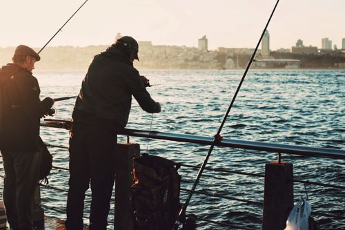 Free Silhouettes of fishermen casting lines at sunset on the Bosphorus waterfront in Istanbul. Stock Photo