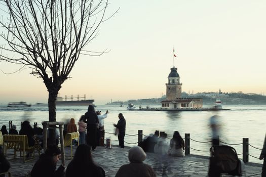 A serene evening scene of Maiden's Tower with people gathered by the water in İstanbul.