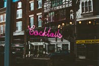 粉红色的霓虹鸡尾酒标志倒映在夜间城市建筑的窗户上