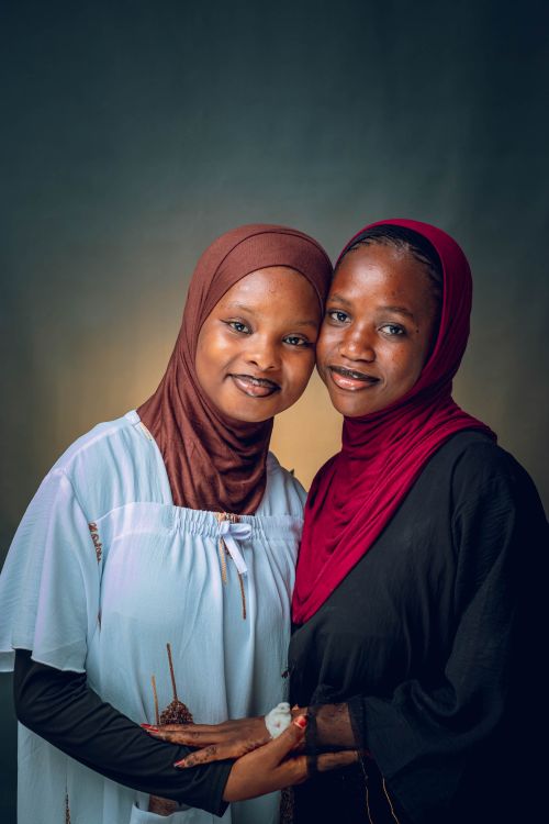 Free Two women wearing hijabs embrace with smiles in a studio setting. Stock Photo