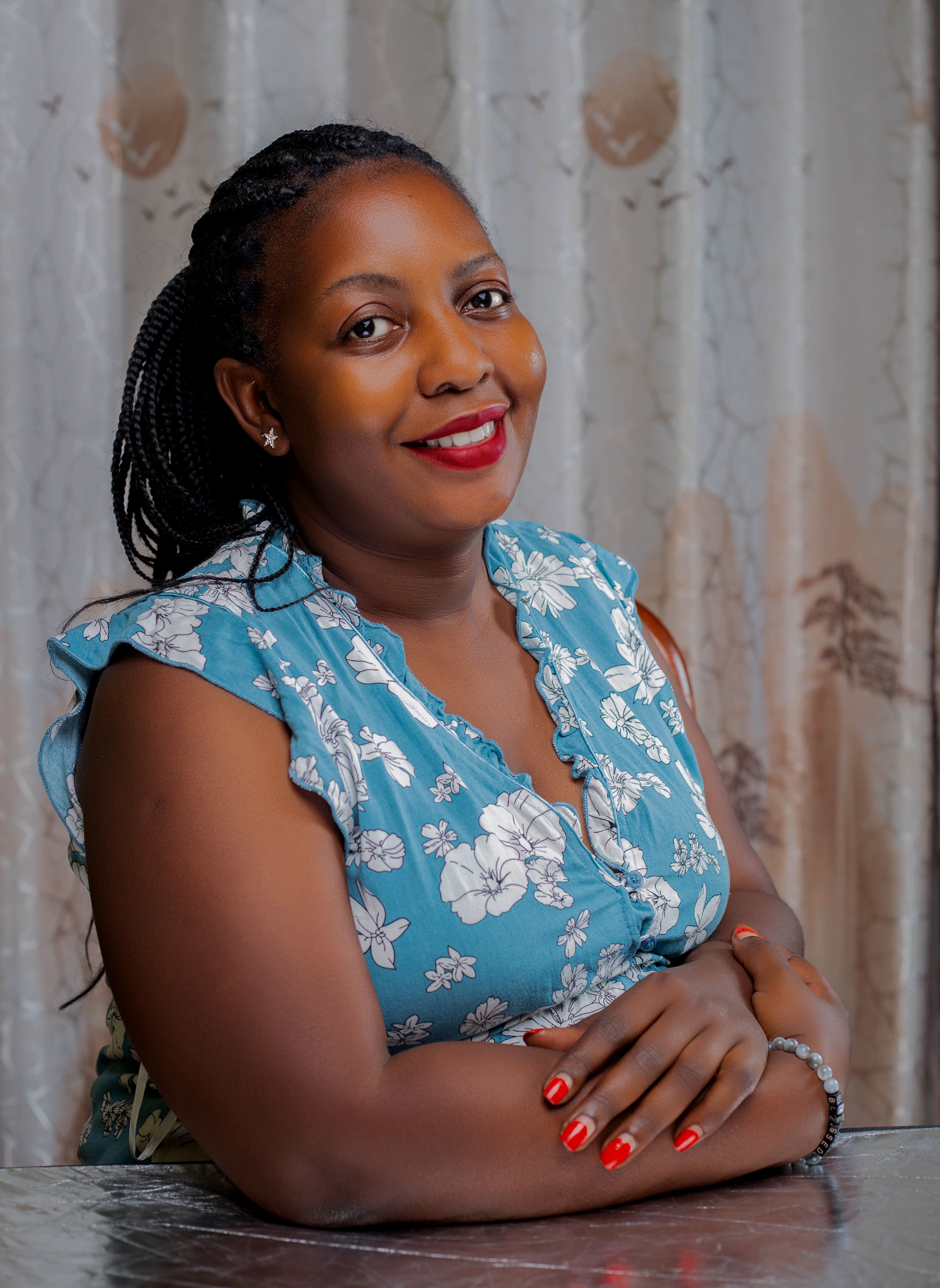 Portrait of a smiling woman in a floral dress with braided hair, indoors.