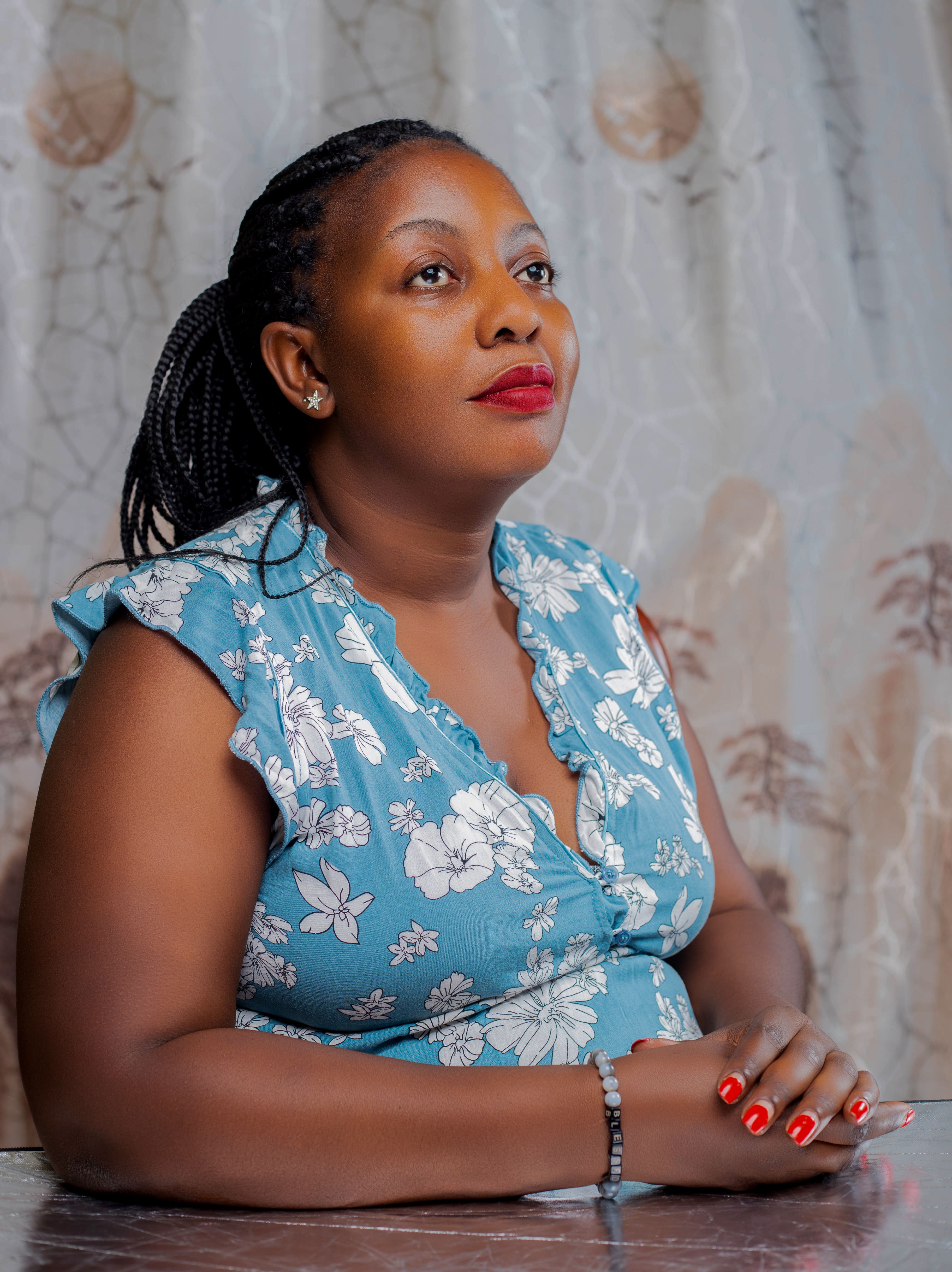 Profile portrait of a woman with braided hair in floral dress, indoors.