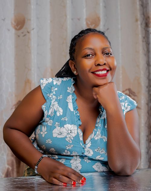 Free Portrait of a cheerful woman indoors wearing a blue floral dress, sitting with a warm smile. Stock Photo