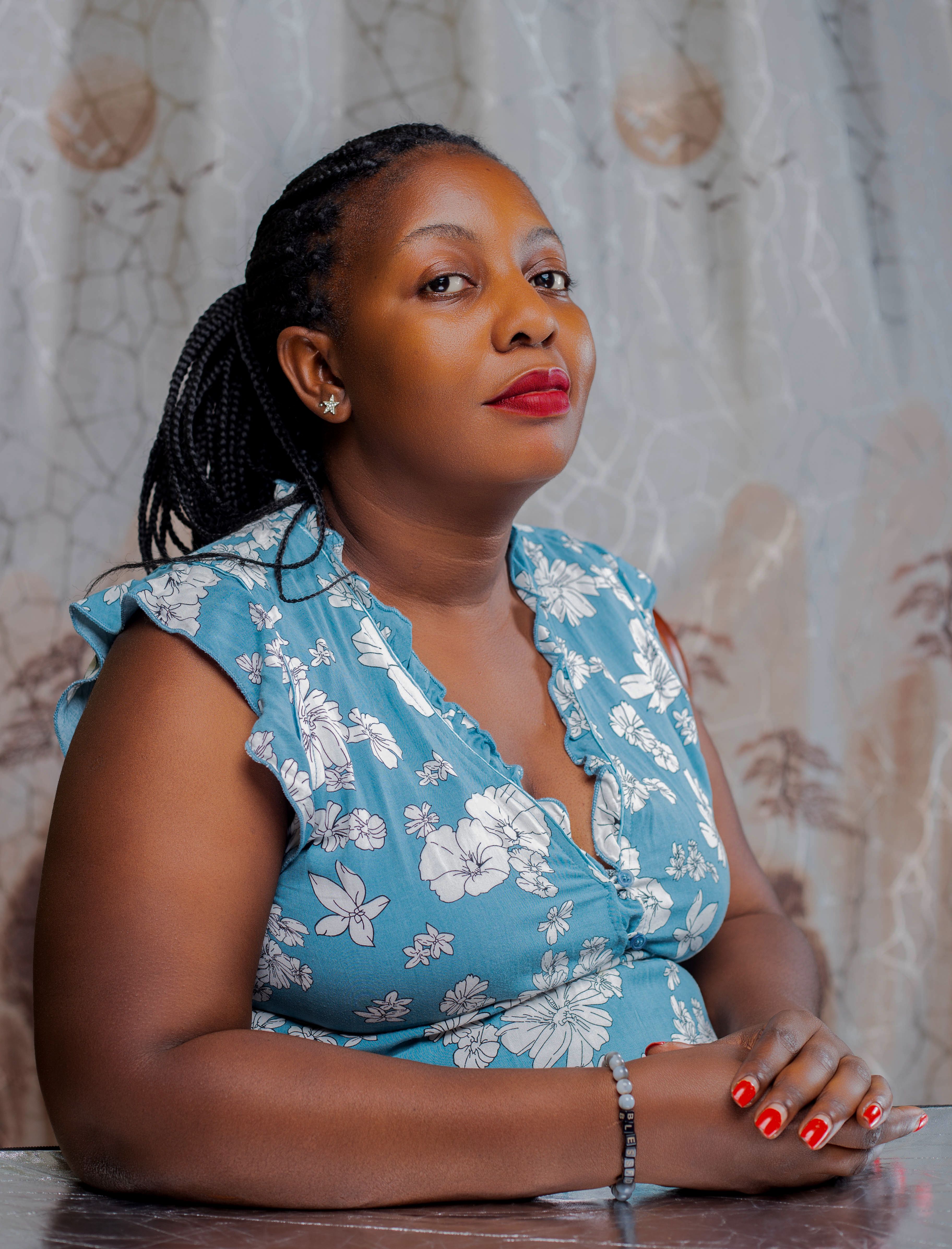 Portrait of a confident woman in a floral dress, posing indoors with a serene expression.